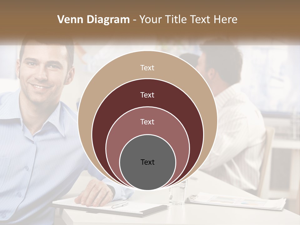 A Man Sitting At A Desk In Front Of A Group Of People PowerPoint Template