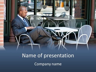 A Man In A Suit Sitting At A Table With A Laptop PowerPoint Template