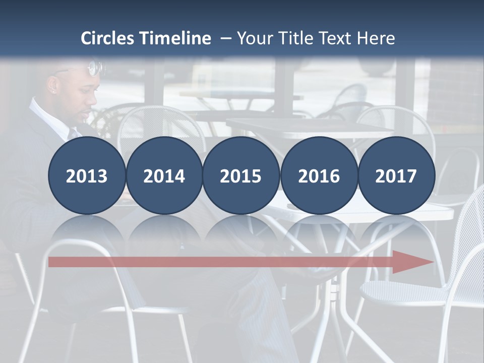 A Man In A Suit Sitting At A Table With A Laptop PowerPoint Template