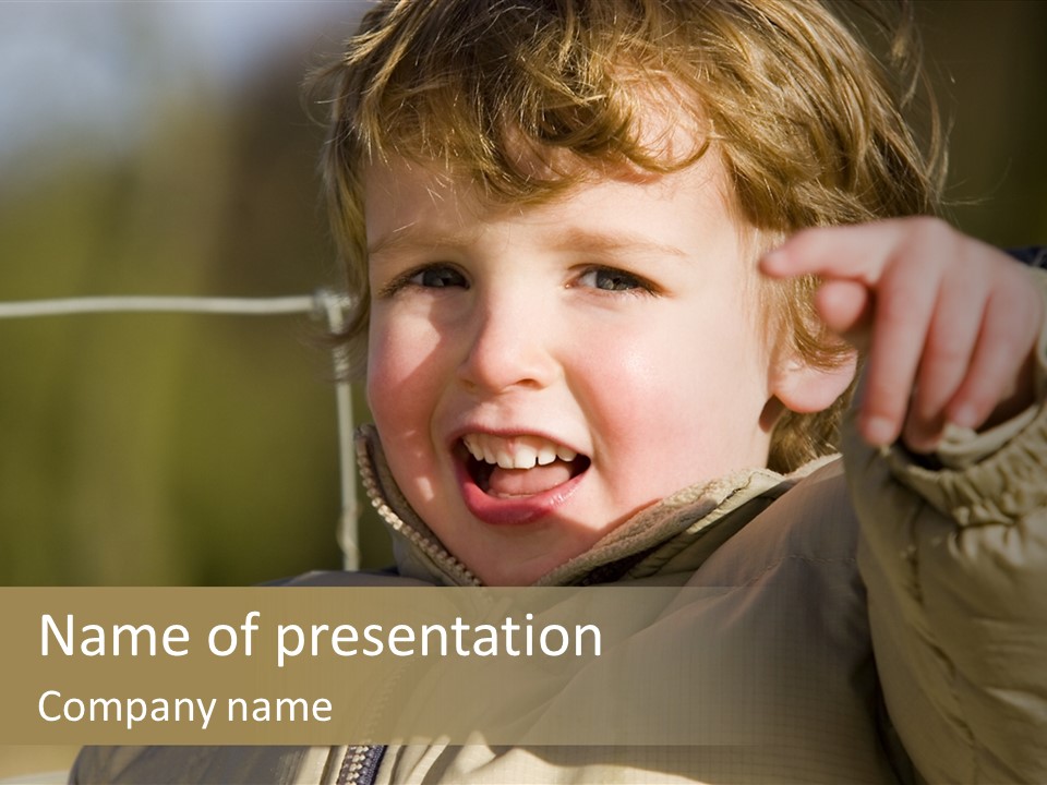 A Young Boy Is Smiling And Pointing At The Camera PowerPoint Template