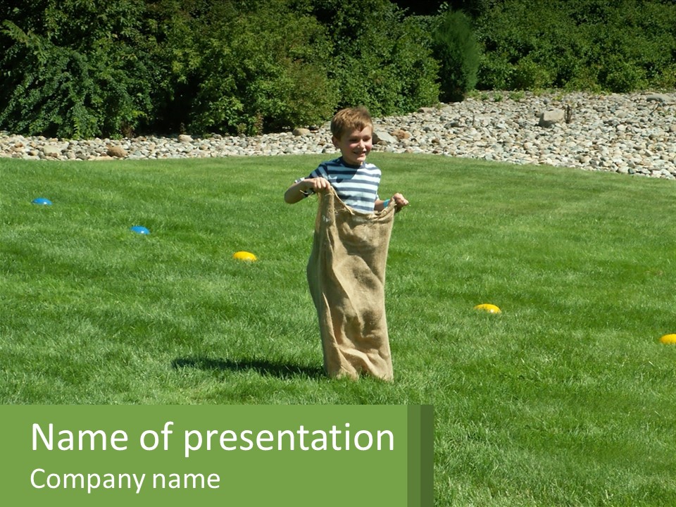 A Young Boy Standing On Top Of A Lush Green Field PowerPoint Template