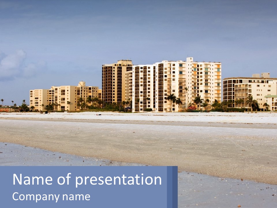A Sandy Beach With Buildings In The Background PowerPoint Template