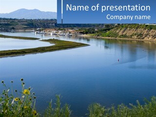 A Large Body Of Water Next To A Lush Green Hillside PowerPoint Template