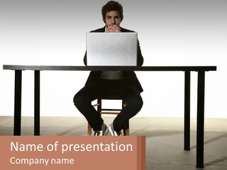 A Man Sitting At A Table Using A Laptop Computer PowerPoint Template