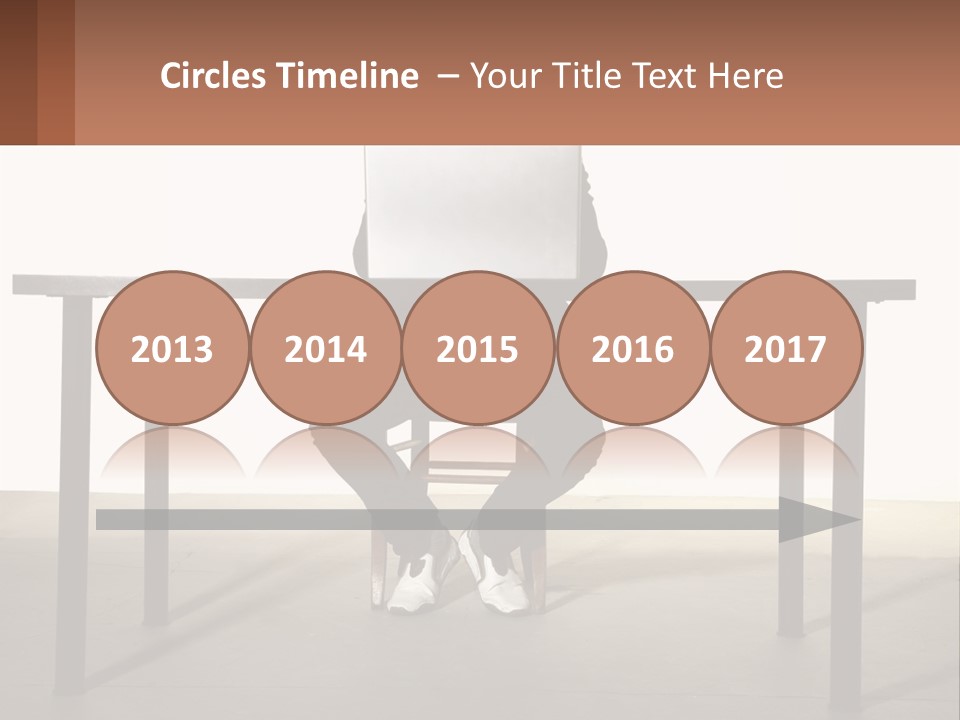 A Man Sitting At A Table Using A Laptop Computer PowerPoint Template