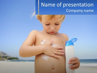 A Young Child Holding A Bottle Of Sunscreen On The Beach PowerPoint Template