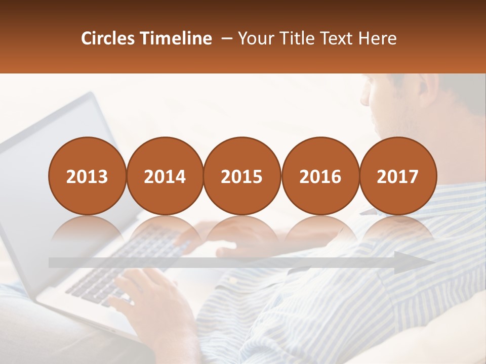 A Man Sitting On A Couch Using A Laptop Computer PowerPoint Template