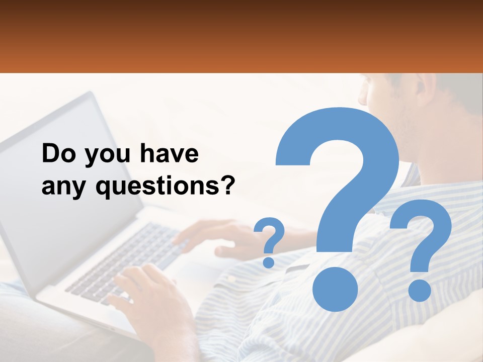 A Man Sitting On A Couch Using A Laptop Computer PowerPoint Template