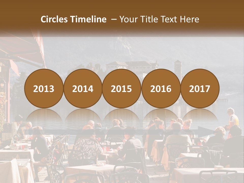 A Group Of People Sitting At A Table In Front Of A Lake PowerPoint Template