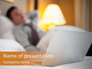 A Man Laying In Bed Next To A Laptop Computer PowerPoint Template