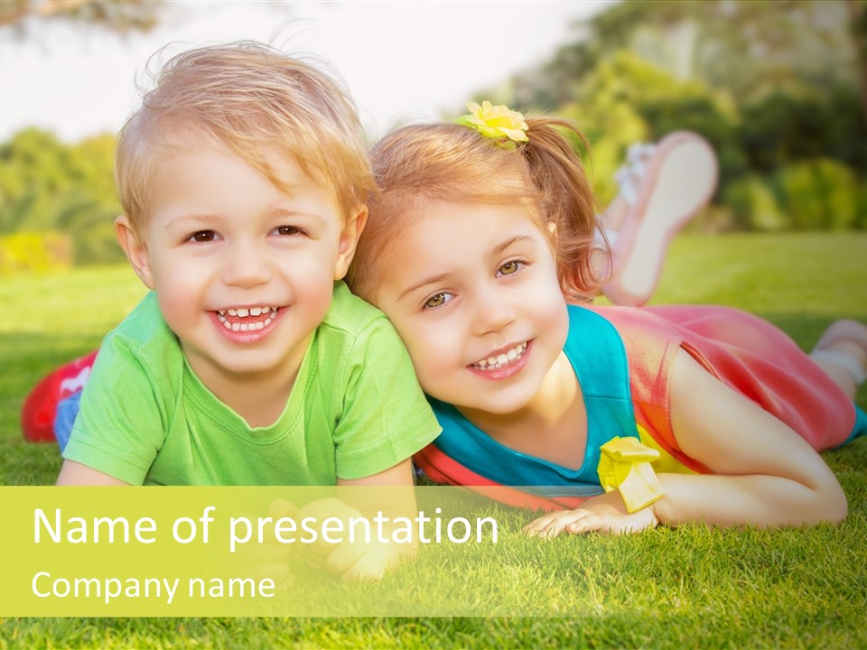 Two Young Children Laying On The Grass In A Park PowerPoint Template
