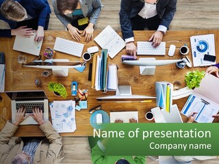 A Group Of People Sitting At A Table Working On Laptops PowerPoint Template