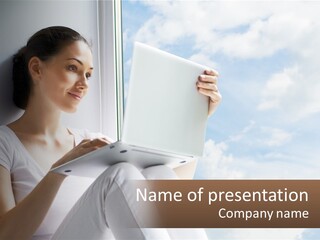 A Woman Sitting On A Window Sill Using A Laptop Computer PowerPoint Template