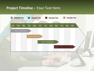 A Group Of People Sitting At A Computer Desk PowerPoint Template