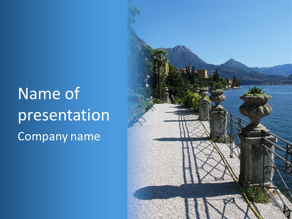 A Stone Walkway Next To A Body Of Water With Mountains In The Background PowerPoint Template