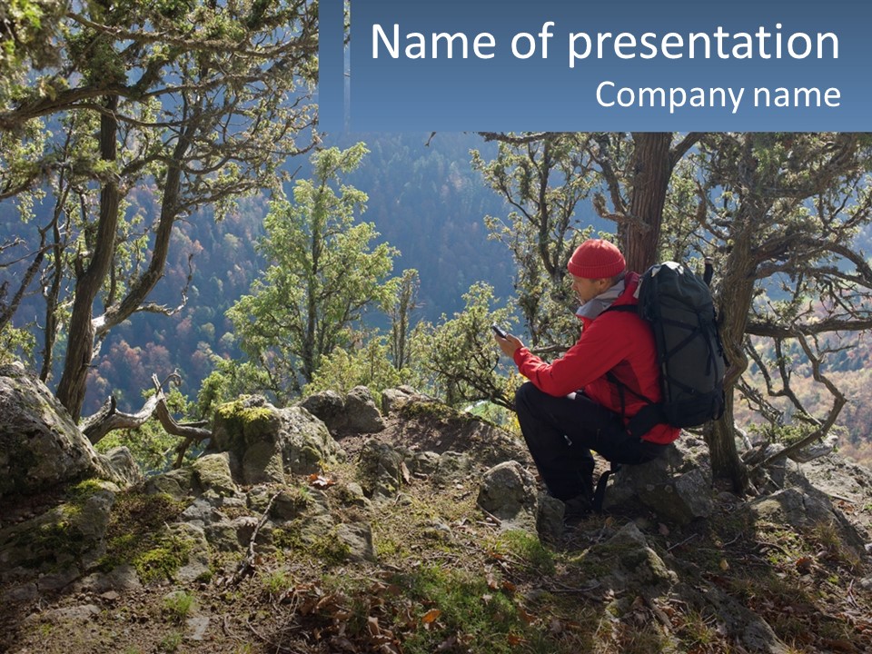 A Man Sitting On A Rock Looking At His Cell Phone PowerPoint Template