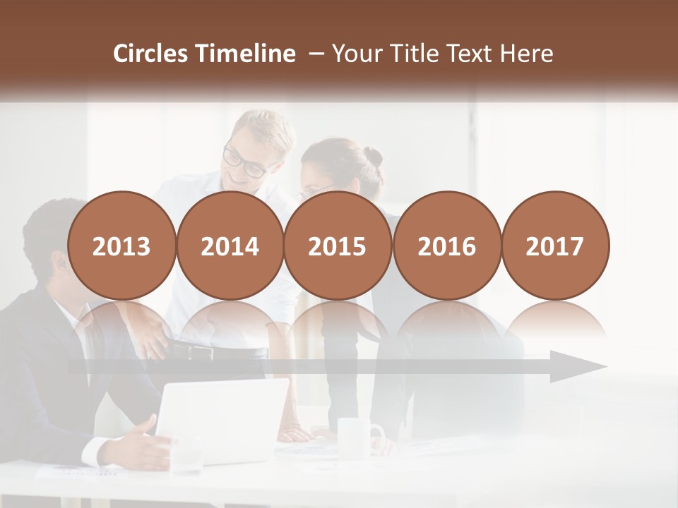 A Group Of People Sitting Around A Table With A Laptop PowerPoint Template