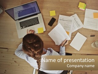 A Woman Sitting At A Table With A Laptop And Papers PowerPoint Template