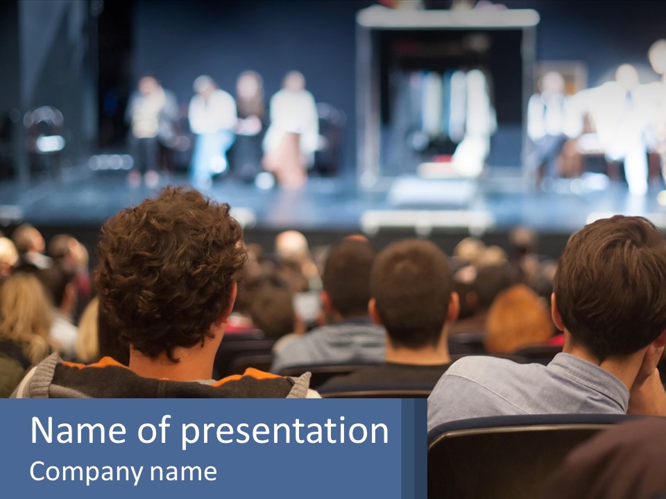 A Group Of People Sitting In Front Of A Stage PowerPoint Template