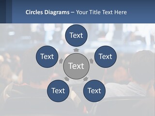 A Group Of People Sitting In Front Of A Stage PowerPoint Template