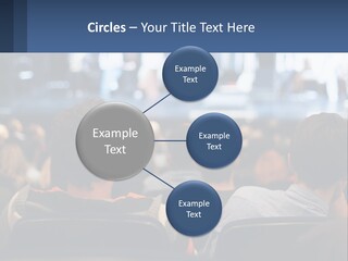 A Group Of People Sitting In Front Of A Stage PowerPoint Template
