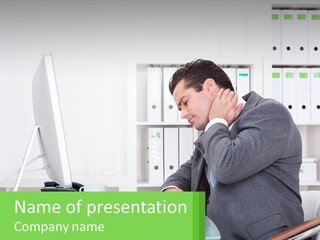 A Man Sitting At A Desk In Front Of A Computer PowerPoint Template