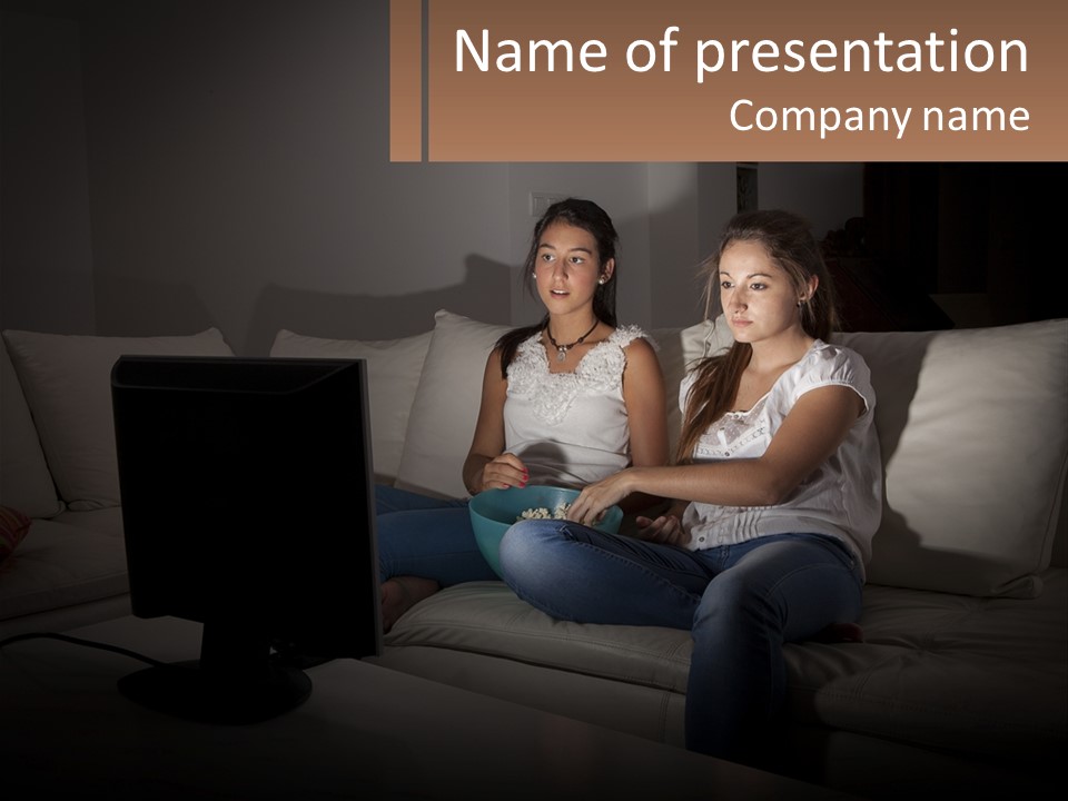 Two Girls Sitting On A Couch Watching A Movie PowerPoint Template
