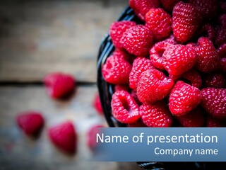 A Basket Filled With Raspberries On Top Of A Wooden Table PowerPoint Template