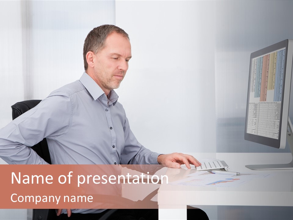 A Man Sitting At A Desk Using A Computer PowerPoint Template