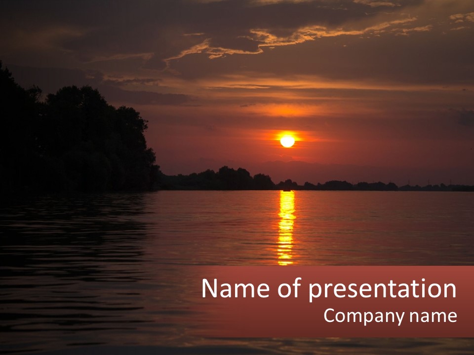A Sunset Over A Body Of Water With Trees In The Background PowerPoint Template