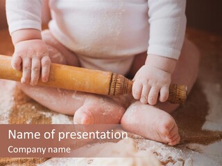 A Baby Holding A Rolling Pin On Top Of A Table PowerPoint Template