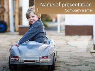 A Young Boy Is Sitting In A Toy Car PowerPoint Template