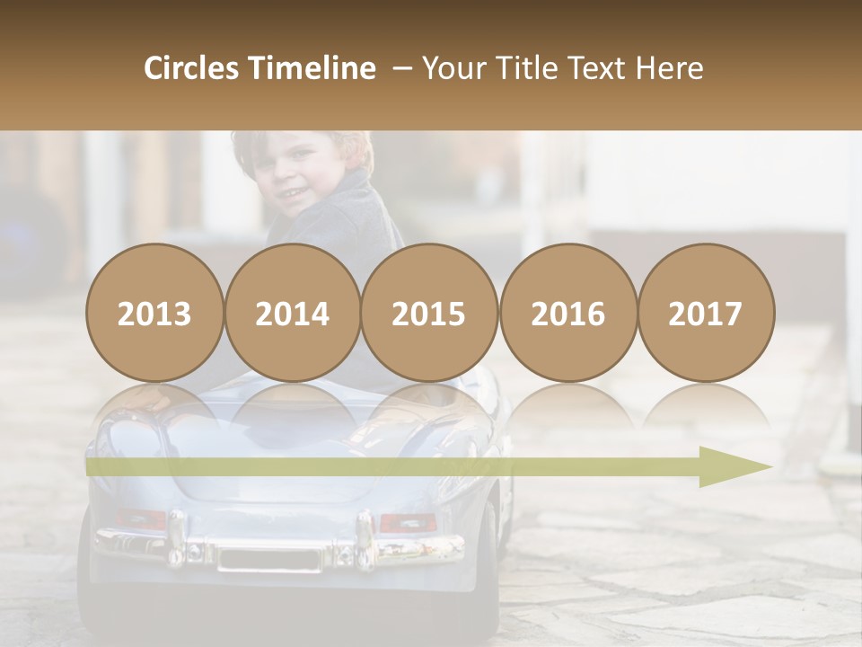 A Young Boy Is Sitting In A Toy Car PowerPoint Template