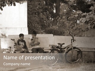 Two Boys Sitting On A Bench In A Park PowerPoint Template