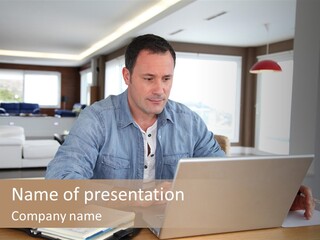 A Man Sitting At A Table Using A Laptop Computer PowerPoint Template