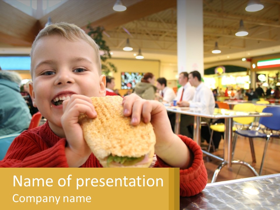 A Young Boy Eating A Sandwich In A Restaurant PowerPoint Template