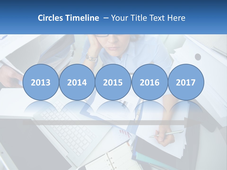 A Woman Sitting At A Desk With A Laptop And Papers PowerPoint Template