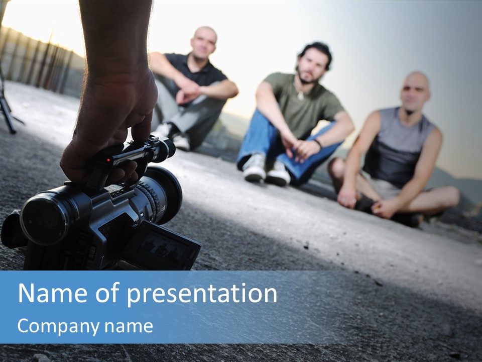 Two Men Sitting On The Ground With A Camera PowerPoint Template