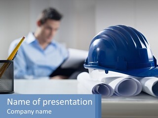 A Man Sitting At A Desk With A Blue Hard Hat On Top Of It PowerPoint Template