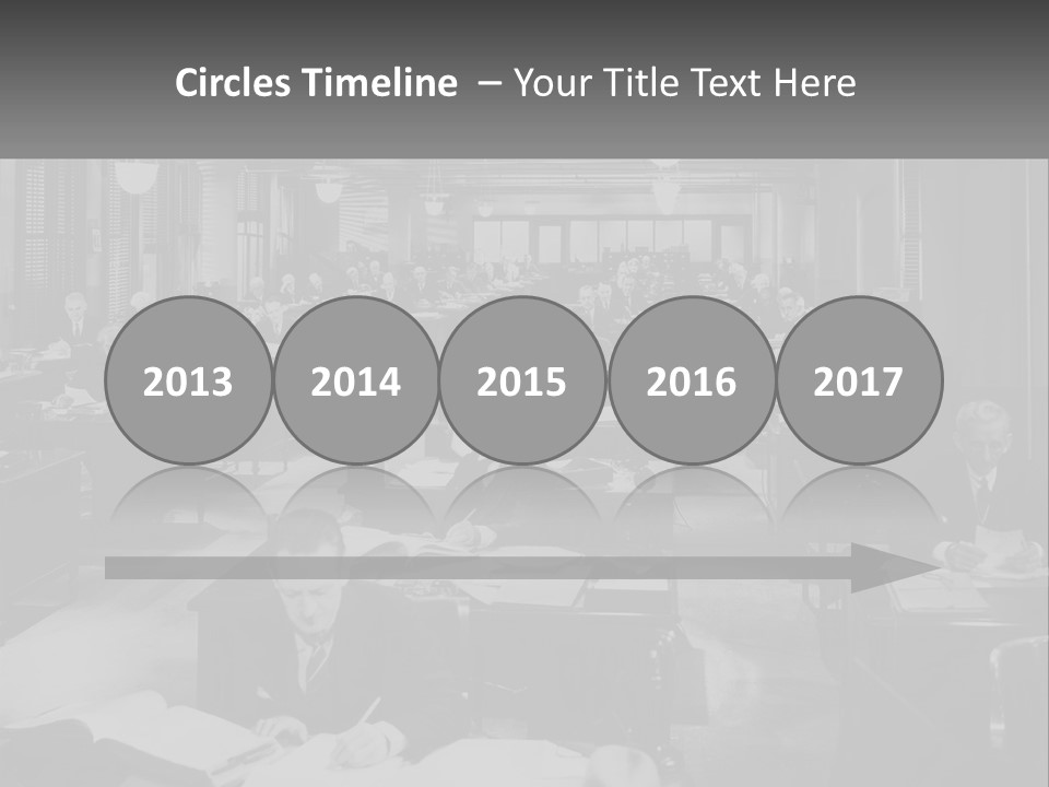 A Group Of People Sitting At Desks In A Room PowerPoint Template