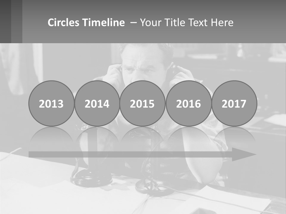 A Man Sitting At A Desk Talking On A Phone PowerPoint Template