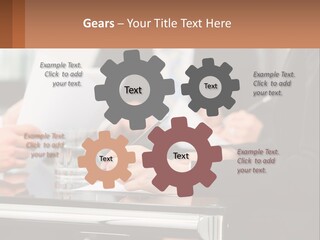 A Group Of People Sitting At A Table Writing On Paper PowerPoint Template