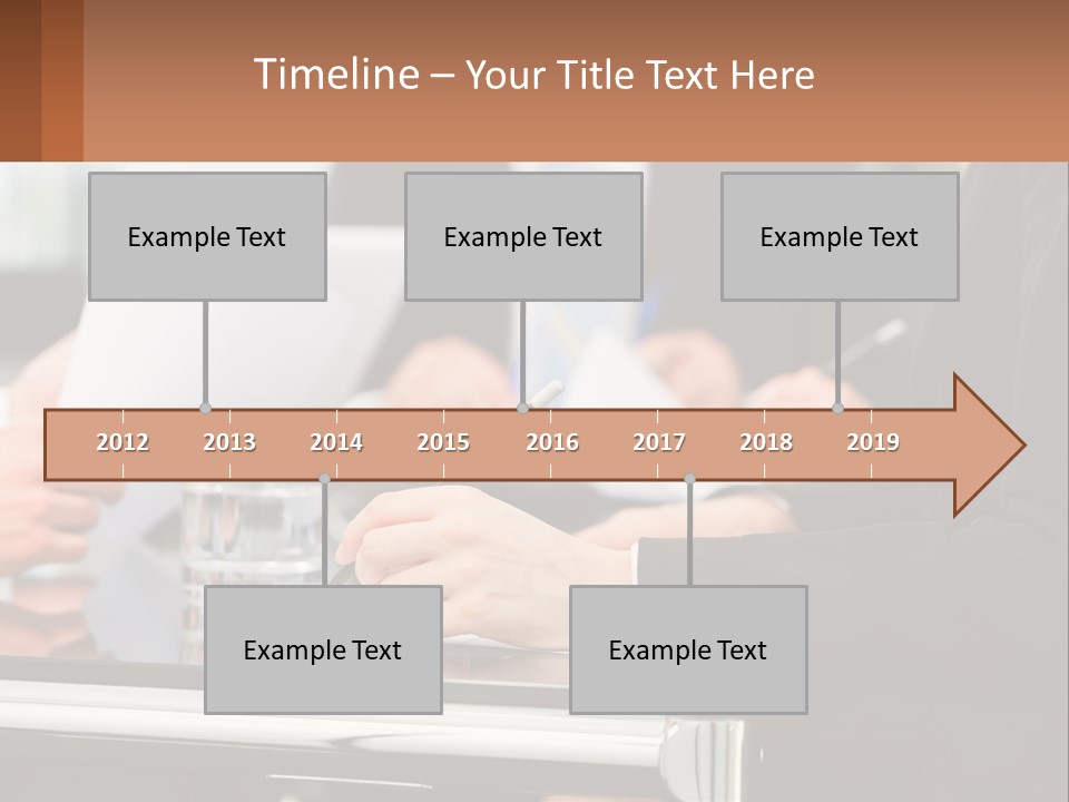 A Group Of People Sitting At A Table Writing On Paper PowerPoint Template