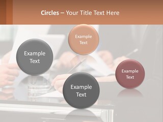A Group Of People Sitting At A Table Writing On Paper PowerPoint Template