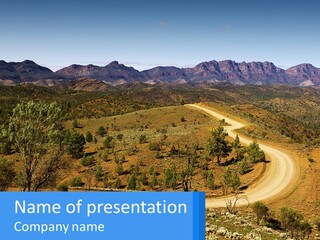 A Dirt Road In The Middle Of A Mountain Range PowerPoint Template