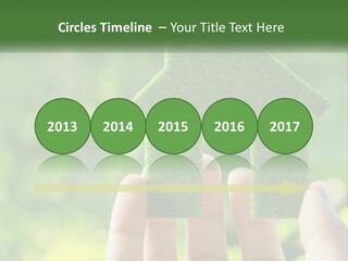 A Person Holding A Small Green House In Their Hands PowerPoint Template