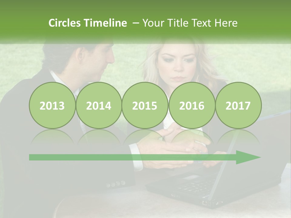 A Man And Woman Sitting At A Table Looking At A Laptop PowerPoint Template