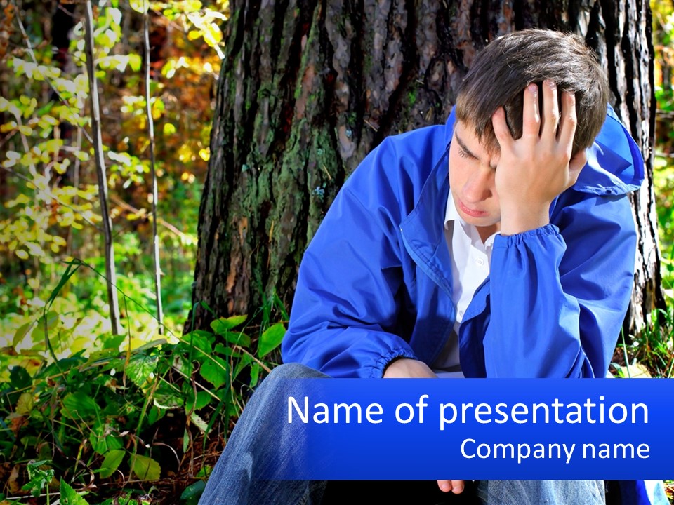 A Man In A Blue Jacket Sitting Next To A Tree PowerPoint Template