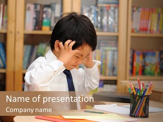 A Young Boy Sitting At A Desk In Front Of A Book Shelf PowerPoint Template