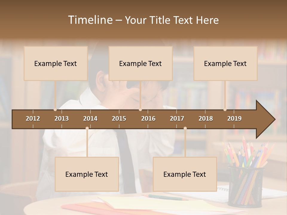 A Young Boy Sitting At A Desk In Front Of A Book Shelf PowerPoint Template